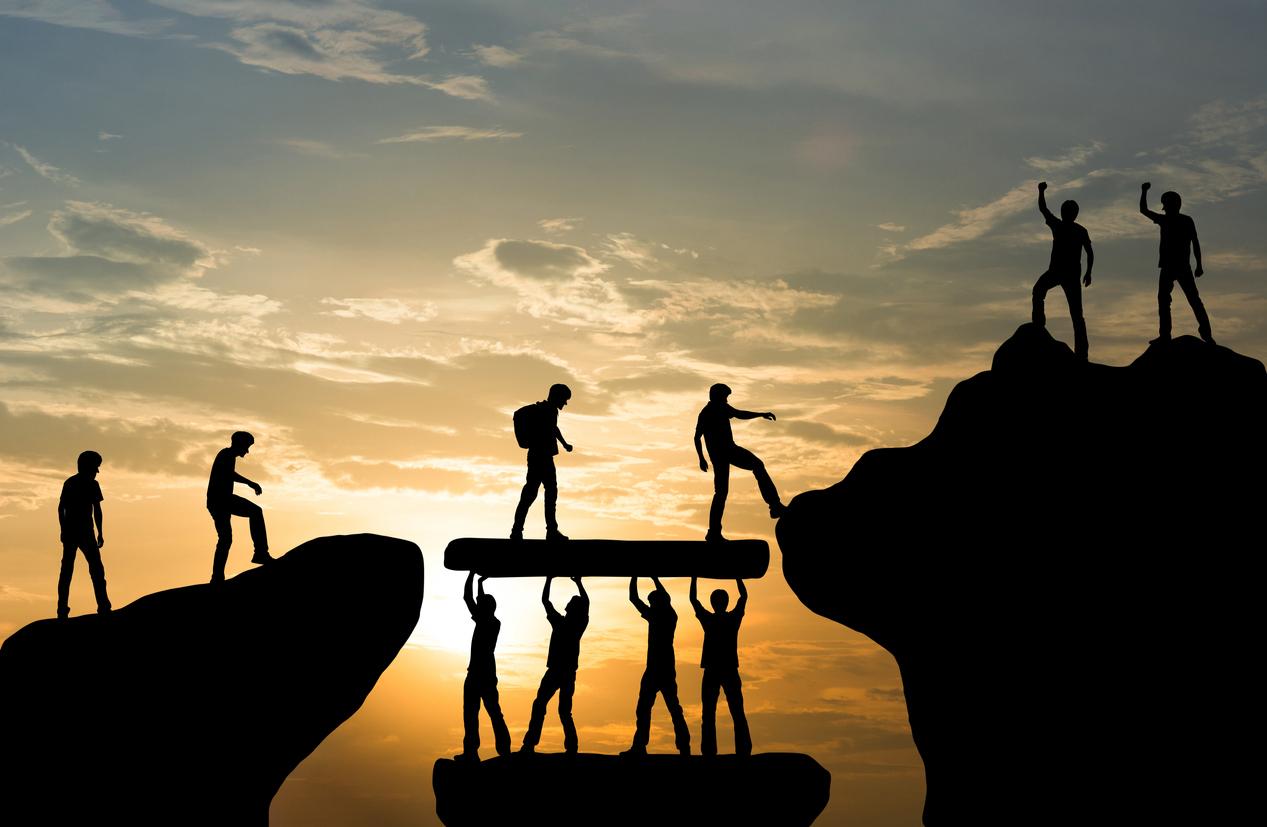 Group of people working together to scale a mountain peak